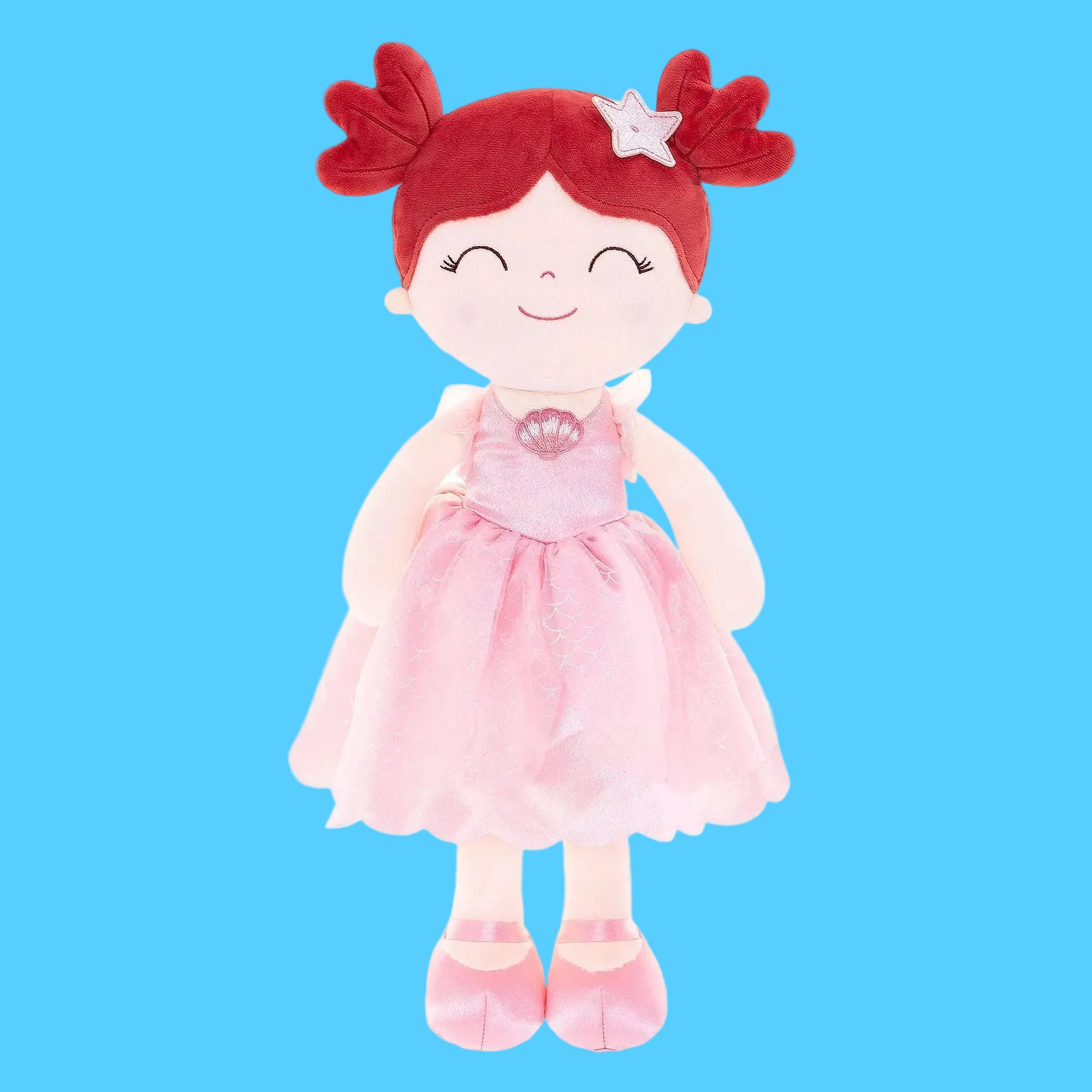 Boneca de pano artesanal inspirada na personagem Princesa Ariel, com duas chiquinhas de cabelo vermelho vibrante e um acessório de estrela-do-mar branca, usando vestido rosa brilhante com detalhe de concha no busto, sobre fundo azul claro.