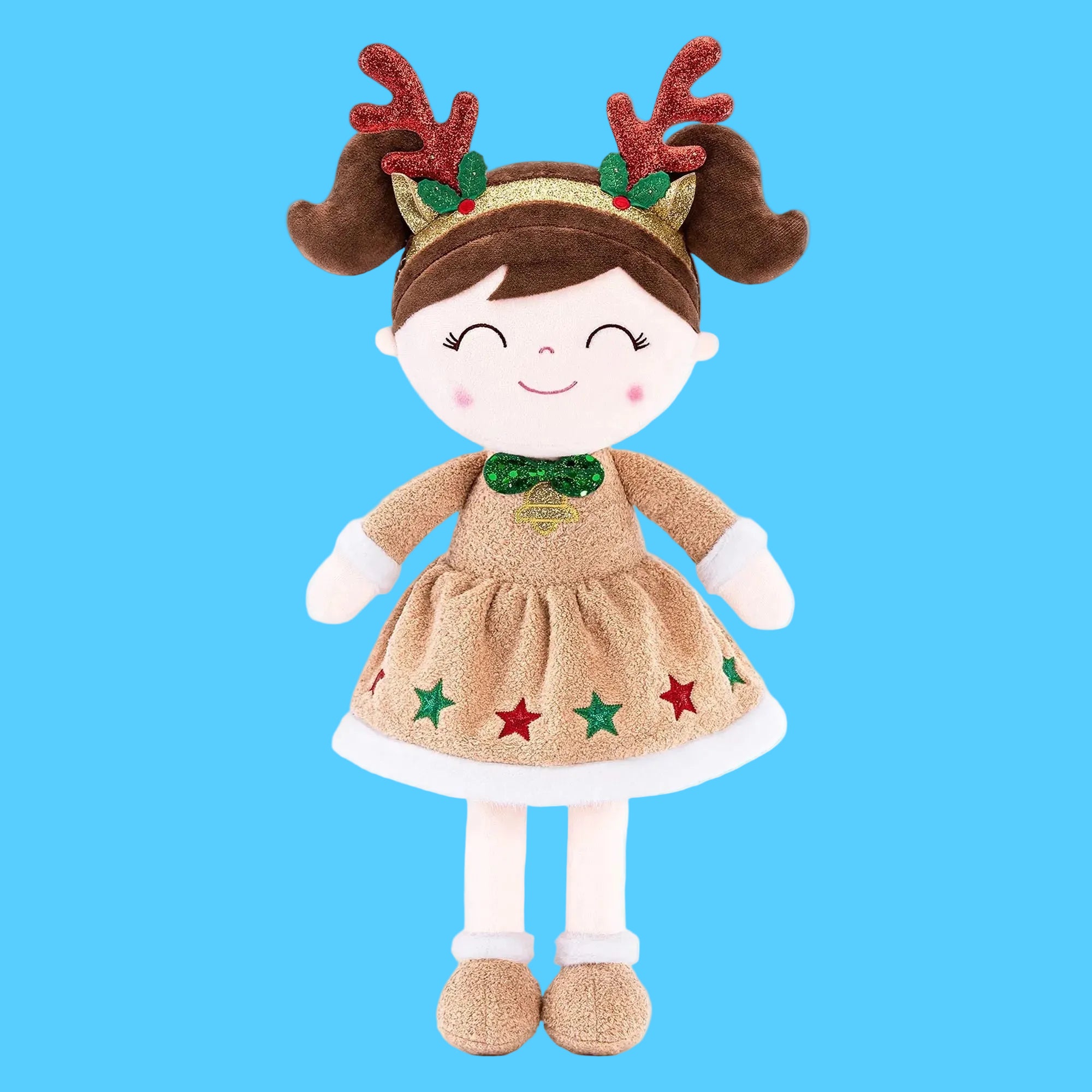 Boneca de pano artesanal com tema de Natal usando vestido dourado brilhante com estampa de estrelas coloridas na barra, gravata borboleta verde no pescoço e tiara com chifres de rena marrons brilhantes, sobre fundo azul claro.
